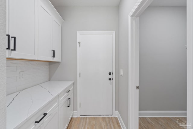 interior space featuring white cabinetry, light stone countertops, and light wood-type flooring