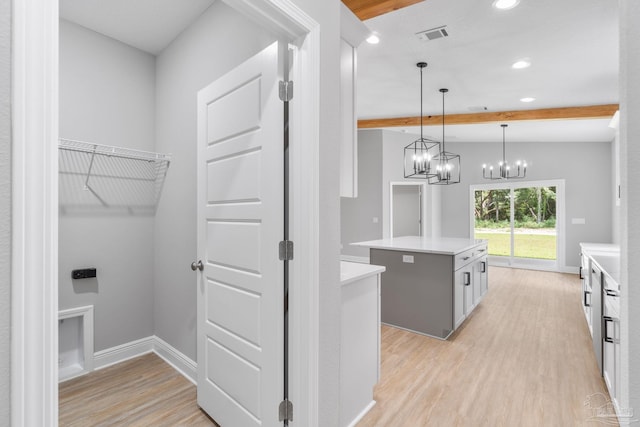 kitchen featuring pendant lighting, white cabinetry, a center island, beam ceiling, and light hardwood / wood-style flooring