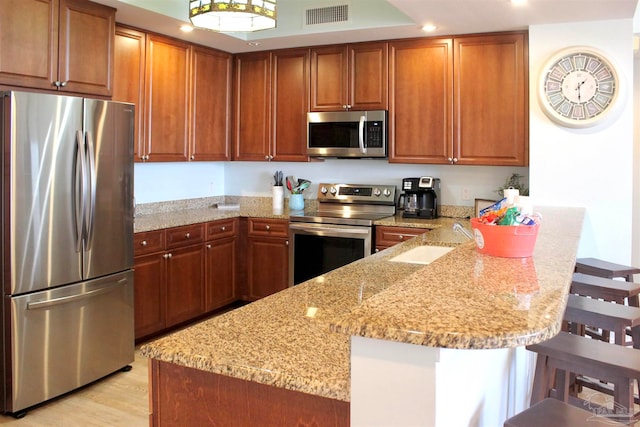 kitchen featuring light stone countertops, a breakfast bar area, light wood-type flooring, and stainless steel appliances