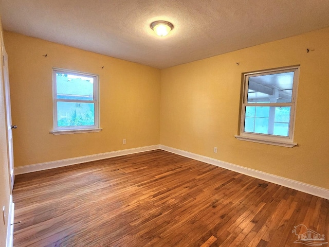 empty room with plenty of natural light, a textured ceiling, and hardwood / wood-style flooring