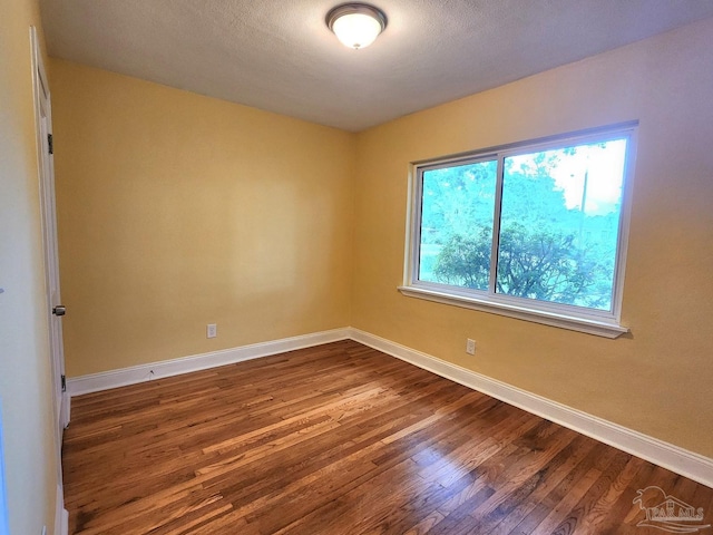 unfurnished room with hardwood / wood-style floors, plenty of natural light, and a textured ceiling