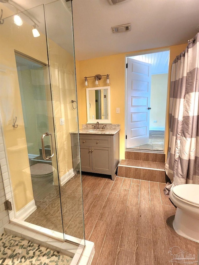 bathroom featuring vanity, toilet, hardwood / wood-style floors, and walk in shower