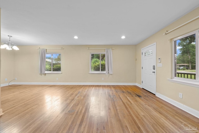 unfurnished living room featuring light wood-style floors, baseboards, and a wealth of natural light