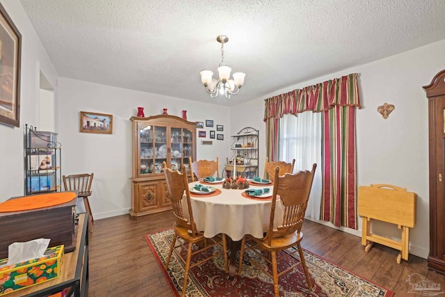 dining area with a notable chandelier, a textured ceiling, and dark hardwood / wood-style flooring