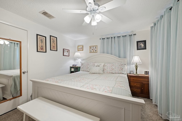 bedroom with a textured ceiling, light colored carpet, and ceiling fan