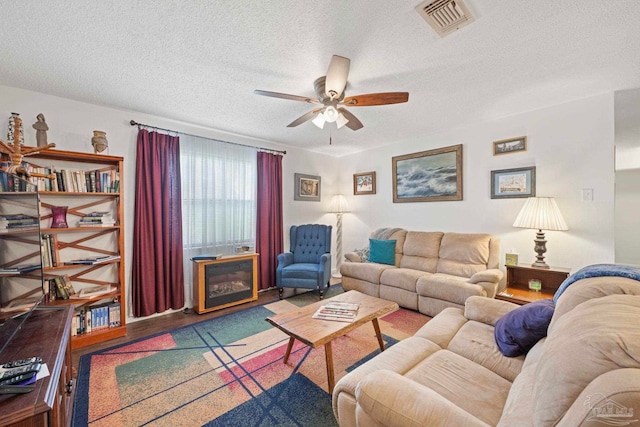 living room with ceiling fan, hardwood / wood-style flooring, and a textured ceiling