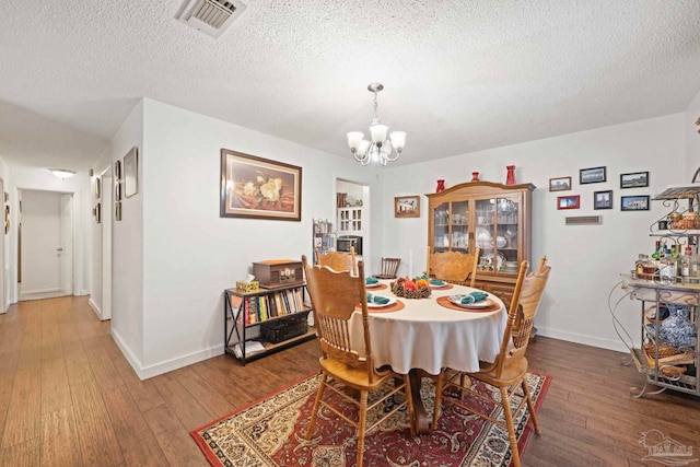 dining room with hardwood / wood-style flooring, a textured ceiling, and a chandelier