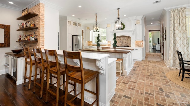 kitchen featuring white cabinetry, stainless steel refrigerator with ice dispenser, decorative backsplash, and crown molding