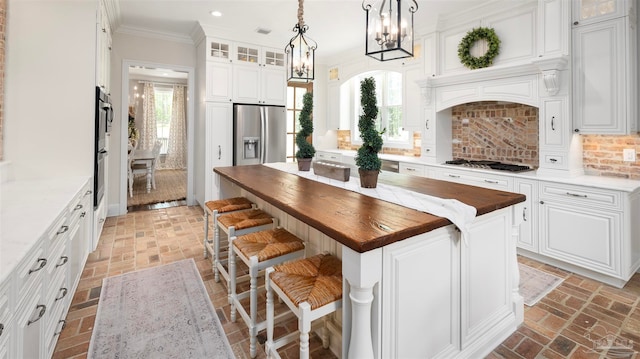 kitchen featuring butcher block counters, a center island, white cabinets, backsplash, and appliances with stainless steel finishes