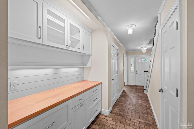 interior space with white cabinetry, ornamental molding, and butcher block counters