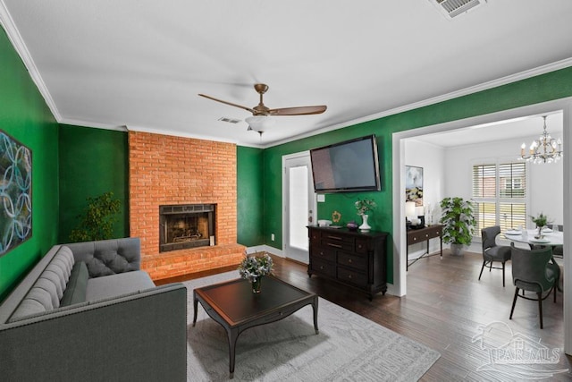 living room with hardwood / wood-style flooring, a fireplace, ornamental molding, and ceiling fan with notable chandelier