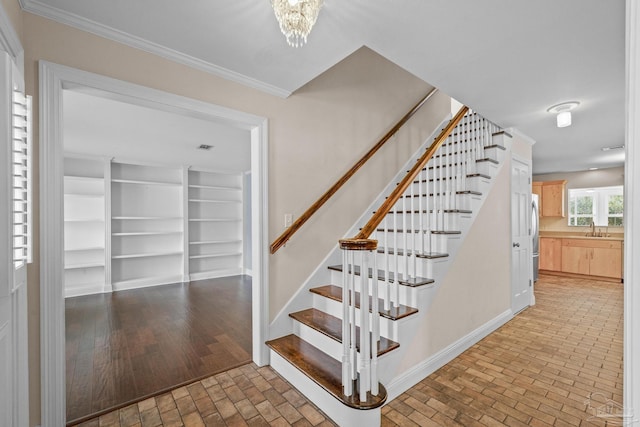 stairway with crown molding, a chandelier, and sink