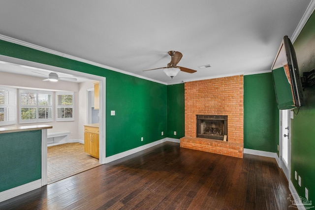 unfurnished living room with hardwood / wood-style flooring, ceiling fan, crown molding, and a fireplace