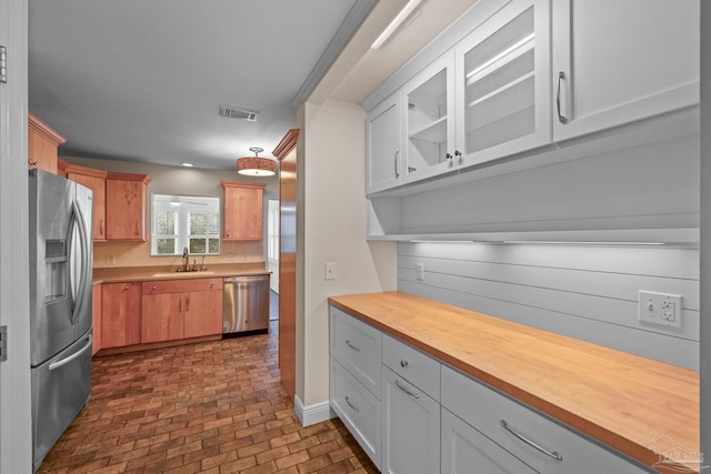 kitchen with appliances with stainless steel finishes, sink, white cabinets, and butcher block countertops