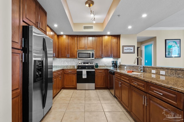 kitchen featuring sink, crown molding, appliances with stainless steel finishes, light stone counters, and rail lighting