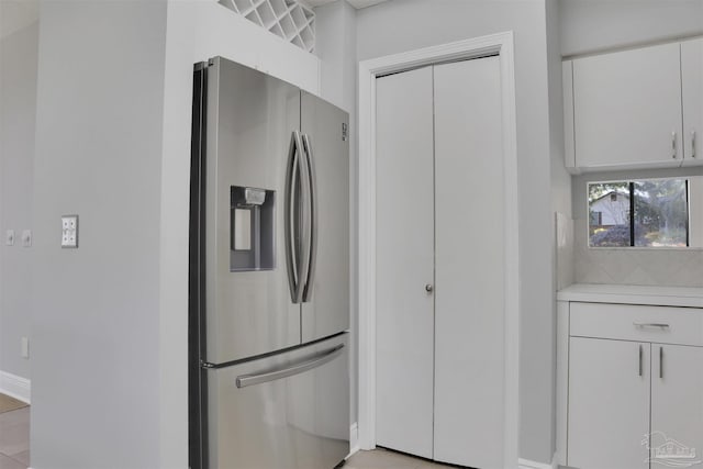 kitchen with stainless steel refrigerator with ice dispenser, white cabinets, and decorative backsplash