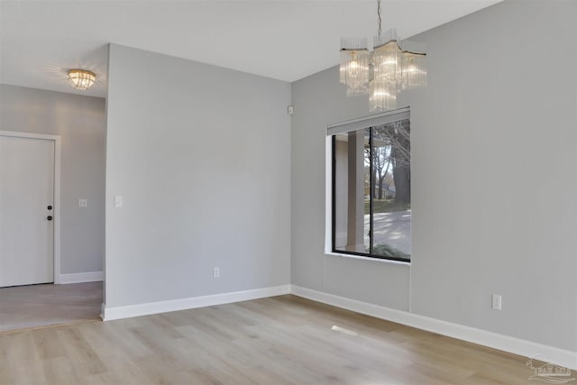 spare room featuring an inviting chandelier and light wood-type flooring