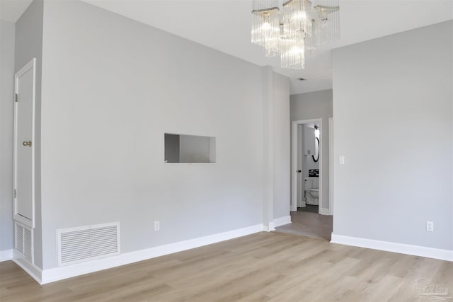 spare room featuring an inviting chandelier and light hardwood / wood-style floors