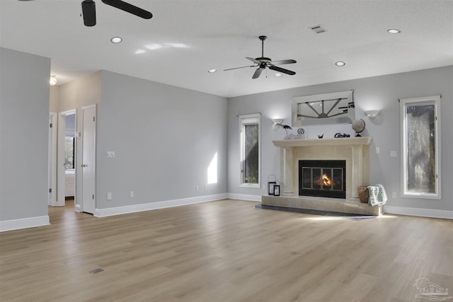 unfurnished living room featuring a healthy amount of sunlight, a fireplace, and light hardwood / wood-style flooring