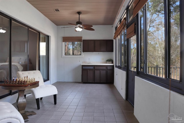 unfurnished sunroom featuring wooden ceiling and ceiling fan