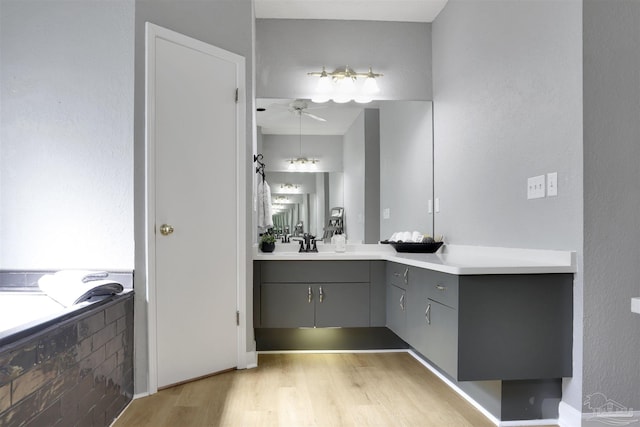 bathroom with hardwood / wood-style flooring, vanity, a tub, and ceiling fan