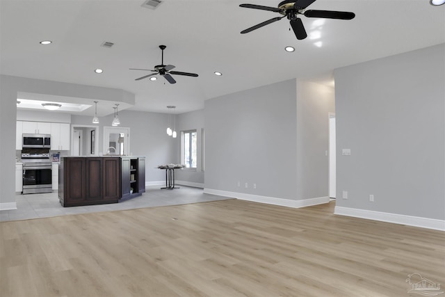 unfurnished living room featuring sink, ceiling fan, and light hardwood / wood-style flooring