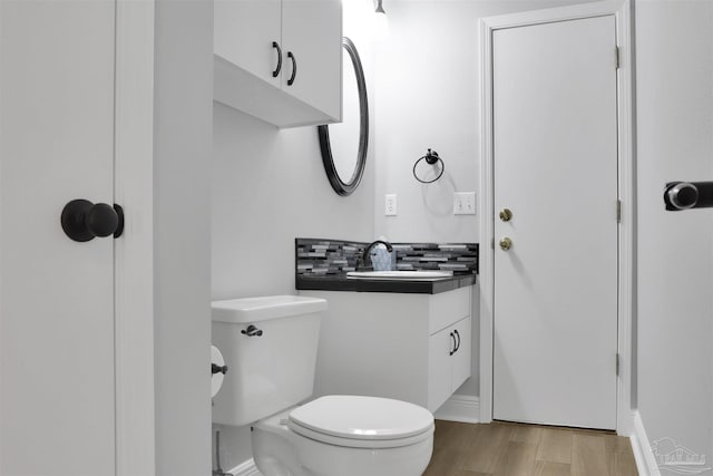 bathroom featuring hardwood / wood-style flooring, vanity, toilet, and backsplash