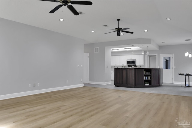 unfurnished living room with sink, ceiling fan, and light hardwood / wood-style flooring