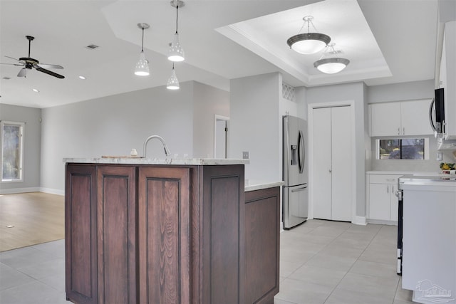 kitchen featuring dark brown cabinetry, white cabinetry, decorative light fixtures, a raised ceiling, and stainless steel appliances