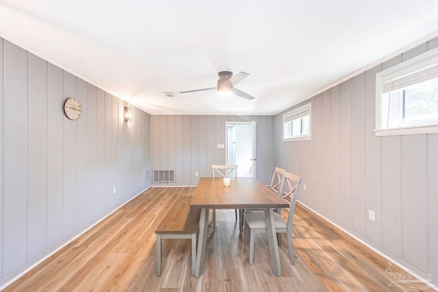 unfurnished dining area featuring wooden walls, light wood-type flooring, and a wealth of natural light