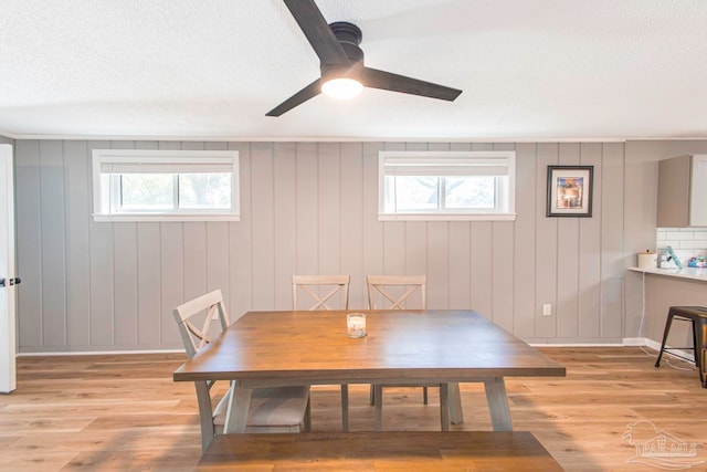 dining area with a wealth of natural light, wooden walls, and light wood-type flooring