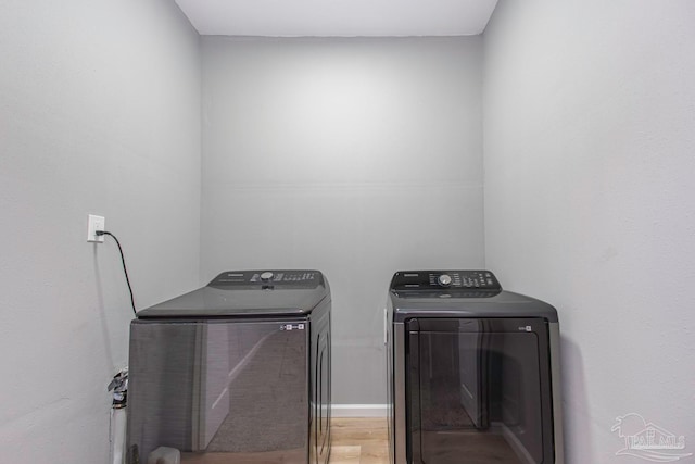 laundry room with wood-type flooring and washing machine and clothes dryer