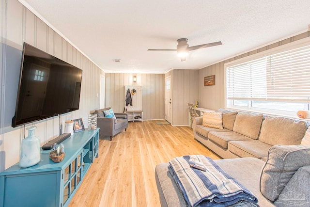 living room with a textured ceiling, light hardwood / wood-style flooring, ceiling fan, and crown molding