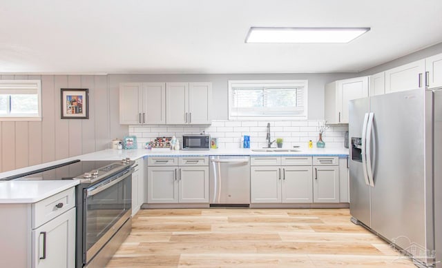 kitchen featuring plenty of natural light, light hardwood / wood-style floors, sink, and appliances with stainless steel finishes