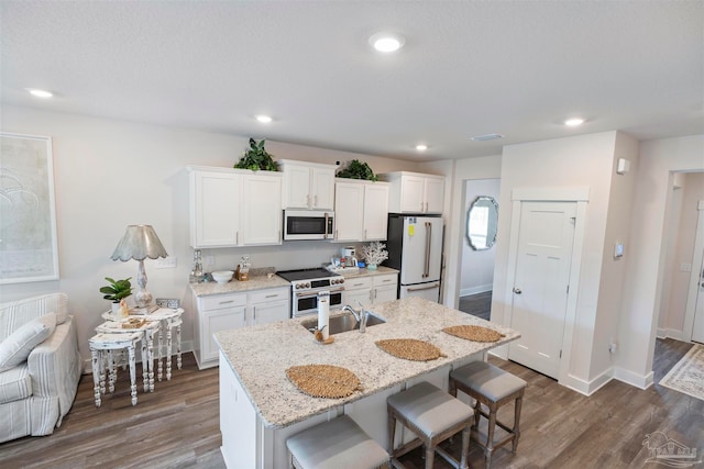 kitchen featuring a breakfast bar, high quality appliances, a center island with sink, and white cabinets