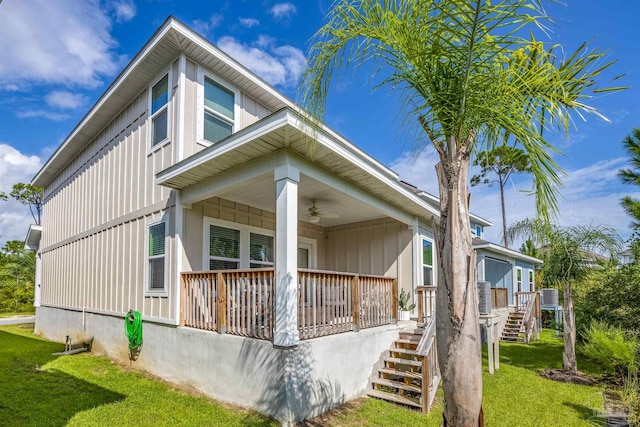 view of side of home featuring a porch, a yard, and ceiling fan