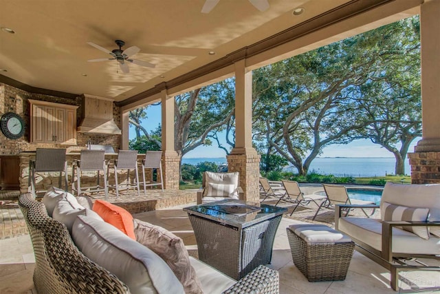 view of patio / terrace featuring ceiling fan, a water view, outdoor lounge area, and exterior bar