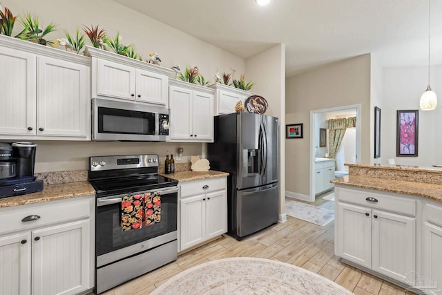 kitchen featuring decorative light fixtures, white cabinets, light stone counters, light hardwood / wood-style floors, and appliances with stainless steel finishes