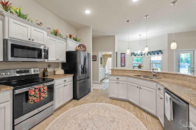 kitchen featuring light wood-type flooring, white cabinets, light stone counters, appliances with stainless steel finishes, and sink