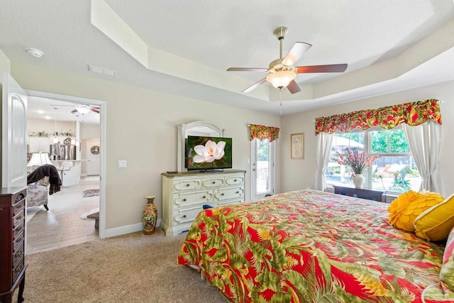 bedroom featuring light hardwood / wood-style flooring, ceiling fan, and a raised ceiling