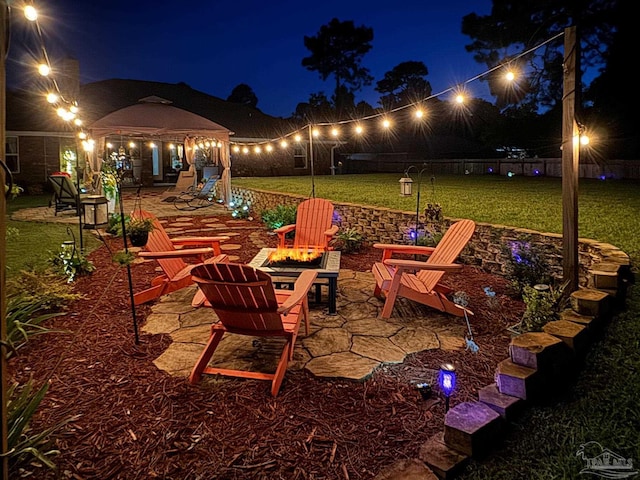 patio at twilight with a yard, a gazebo, and an outdoor fire pit