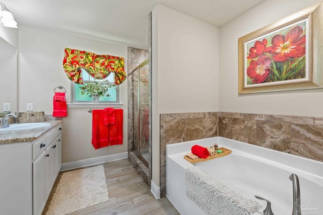 bathroom featuring vanity, plus walk in shower, a textured ceiling, and hardwood / wood-style floors