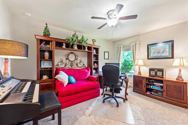 carpeted home office featuring a textured ceiling and ceiling fan