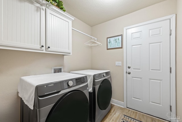 laundry area featuring separate washer and dryer, cabinets, and a textured ceiling