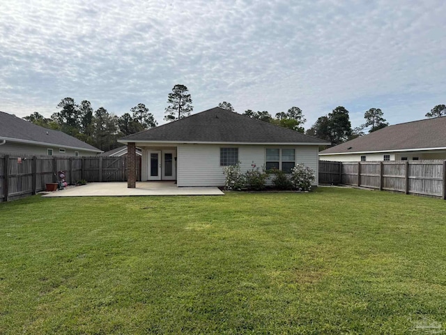 rear view of house featuring a patio, a fenced backyard, a lawn, and french doors