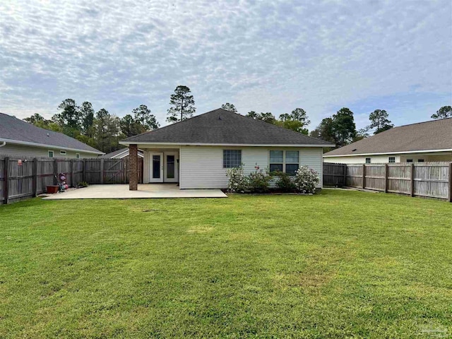 rear view of property with a fenced backyard, a yard, a patio area, and french doors