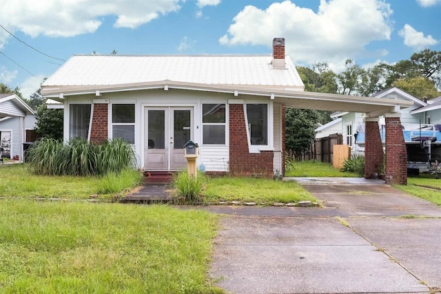 view of front of house featuring french doors, a chimney, brick siding, metal roof, and fence