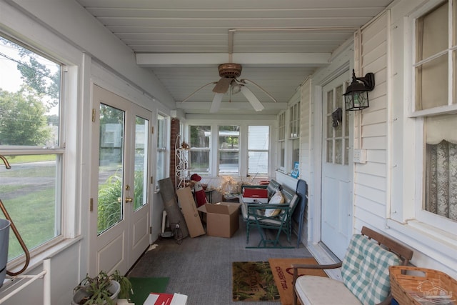 sunroom / solarium featuring beamed ceiling, ceiling fan, and a healthy amount of sunlight