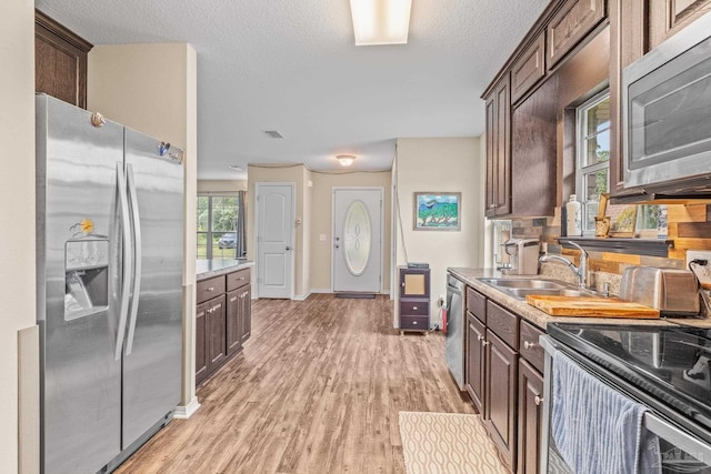 kitchen featuring dark brown cabinets, stainless steel appliances, a wealth of natural light, and light wood-type flooring