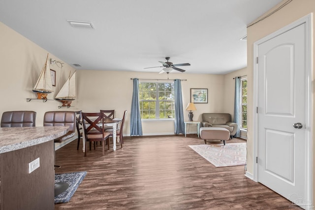 living room featuring dark wood-type flooring and ceiling fan